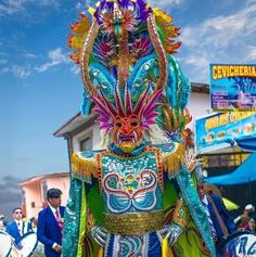 an elaborately decorated carnival float in the middle of a street with people walking by