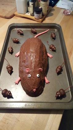 a cake shaped like a rat on a pan with chocolate mouses around the edges