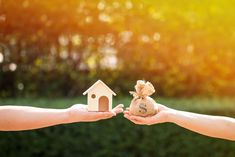 two people holding out their hands to each other with a house and money bag in front of them