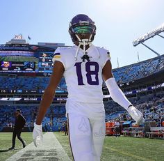 a football player walking on the field at a stadium wearing a helmet and uniform with his hands in his pockets