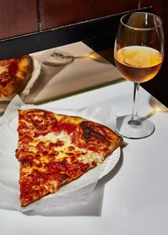 two slices of pizza and a glass of wine on a table