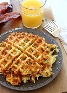 some waffles on a plate next to a glass of orange juice and bacon