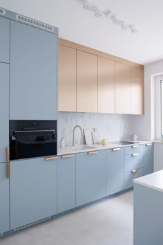 a kitchen with light blue cabinets and white counter tops, along with a black stove top oven