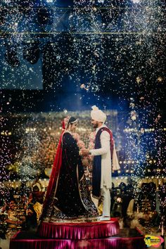 two people standing on top of a stage with confetti falling from the sky