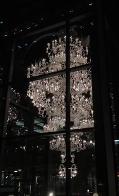 a large chandelier hanging from the side of a tall glass building at night