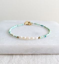 Beautiful Natural Turquoise beads and delicate Freshwater Pearls are used to create this modern boho beaded bracelet. D E T A I L S - Made with high quality Turquoise and Freshwater Pearl beads. - Five delicate Freshwater Pearls are centered among stunning natural Turquoise beads. - Non-tarnish 14k Gold-Filled chain adjuster. Gold-filled is a wonderful alternative to solid gold, and unlike gold plating, it is made to last a lifetime. - Lobster clasp closure. - Comes with a 1 inch adjuster. S I Z Turquoise And Pearl Bracelets, Handmade Elegant Amazonite Beaded Bracelets, Handmade Turquoise Amazonite Bracelets, Elegant Amazonite Beaded Bracelets, Turquoise Heishi Beads Bracelet With Tiny Beads, Bohemian Pearl Bracelet With Colorful Beads And Adjustable Fit, Elegant Turquoise Beaded Bracelets With Tiny Beads, Bohemian Adjustable Pearl Bracelet With Colorful Beads, Bohemian Adjustable Pearl Bracelet With Round Beads