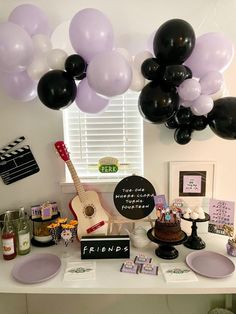 a table topped with black and white balloons next to a guitar on top of a counter