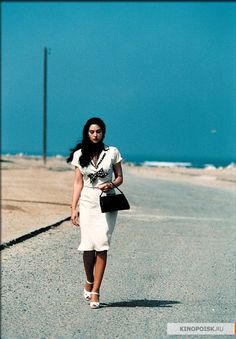 a woman is walking down the road with her hand on her hip while wearing a white dress