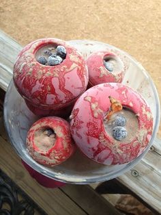 three red vases with holes in them sitting on a wooden table next to a fence