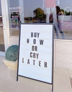 a sign that says buy now or cry later in front of a storefront window