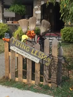 a wooden fence with brooms on top of it and a sign that says flying lessons