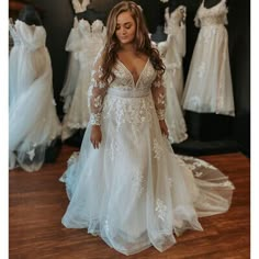 a woman standing in front of wedding gowns