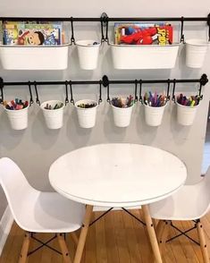 two white chairs and a table with some books on the wall behind them in a room