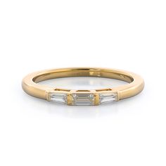 a yellow gold band with three baguettes on the side and two diamonds in the middle