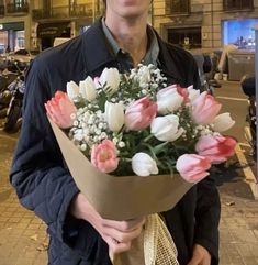 a man holding a bouquet of flowers on the street