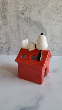 a small figurine of a dog laying on top of a house