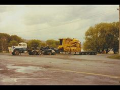 two large trucks are parked on the side of the road in front of some trees