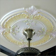 an ornate ceiling fan in a room with white and gold decor on the ceiling,