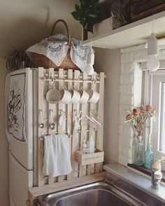 a white refrigerator freezer sitting next to a metal sink under a window with pots and pans on it