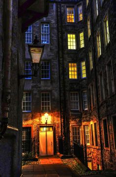 an old building with many windows lit up by street lights and a lamp on the side