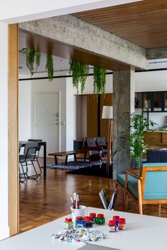 a living room filled with furniture and lots of greenery hanging from the ceiling next to a dining table