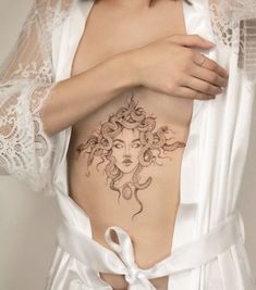 a woman with a tattoo on her stomach is wearing a white robe and posing for the camera