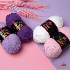 four balls of yarn sitting next to each other on a pink and purple tablecloth