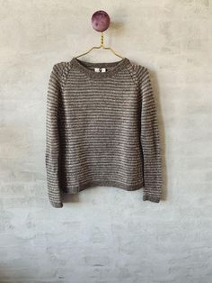 a gray sweater hanging on a white wall