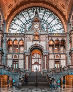 the inside of a building with many stairs and people walking up it in front of an arched ceiling