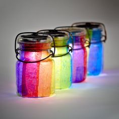 three jars filled with rainbow colored liquid sitting next to each other