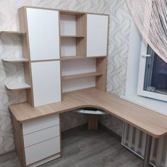 a corner desk with white cabinets and drawers