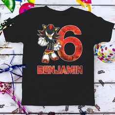 a black t - shirt with the number six on it and an image of benjamin