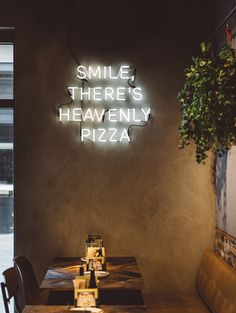 there is a neon sign that says smile, there's heavenly pizza on the wall