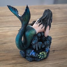 a mermaid figurine sitting on top of a wooden table