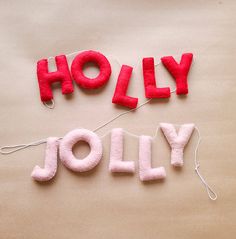 the word holly spelled out in red felt and string on top of a brown surface