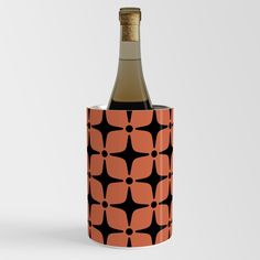 a bottle of wine with an orange and black flower pattern on the top is in a cup holder