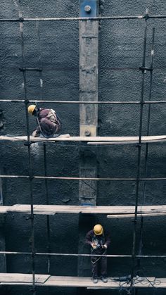 two men working on the side of a building with scaffolding around them,