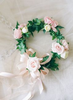 a wedding wreath with pink roses and greenery on the side, sitting on a bed