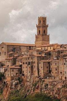 an old town with stone buildings and a clock tower in the background, surrounded by green trees