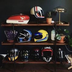 several helmets are lined up on a shelf in front of a wall with a lamp and potted plant