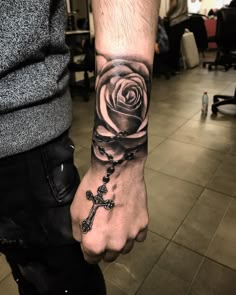 a man with a cross and rose tattoo on his arm is holding the hand of a woman