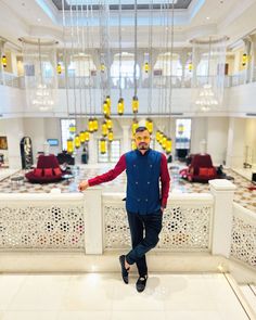 a man standing in the middle of a room with chandeliers hanging from the ceiling