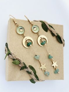 four pairs of earrings on top of a piece of paper next to some green leaves