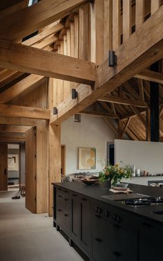 an open kitchen with wooden beams and black counter tops, along with dark wood cabinets