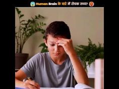 a young man sitting at a table with a book and pen in front of him