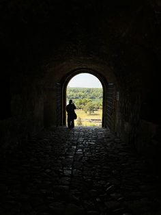 a person standing in a dark tunnel with the light at the end looking into the distance