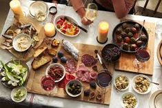 a table filled with food and drinks on top of a wooden cutting board next to candles