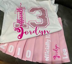 pink and white birthday shirts with the number thirteen printed on them, sitting next to each other