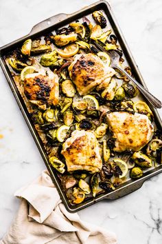 chicken and brussel sprouts in a baking pan with a fork on the side