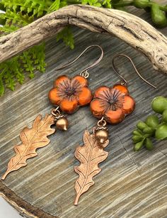 the earrings are made with copper and orange glass flowers, leaves and acorns